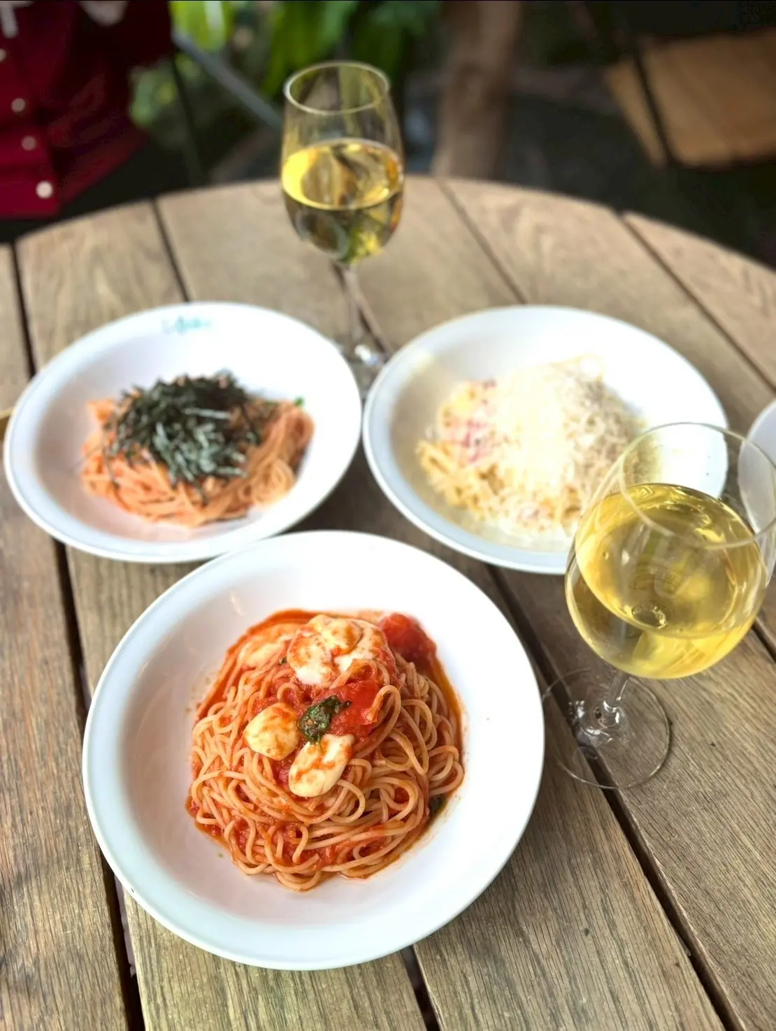 新宿御苑ラ・ボエムで楽しんだランチ。パスタ3種と白ワインをテーブルに並べた写真。同期ランチ会で味わったイタリアンランチの一コマ。