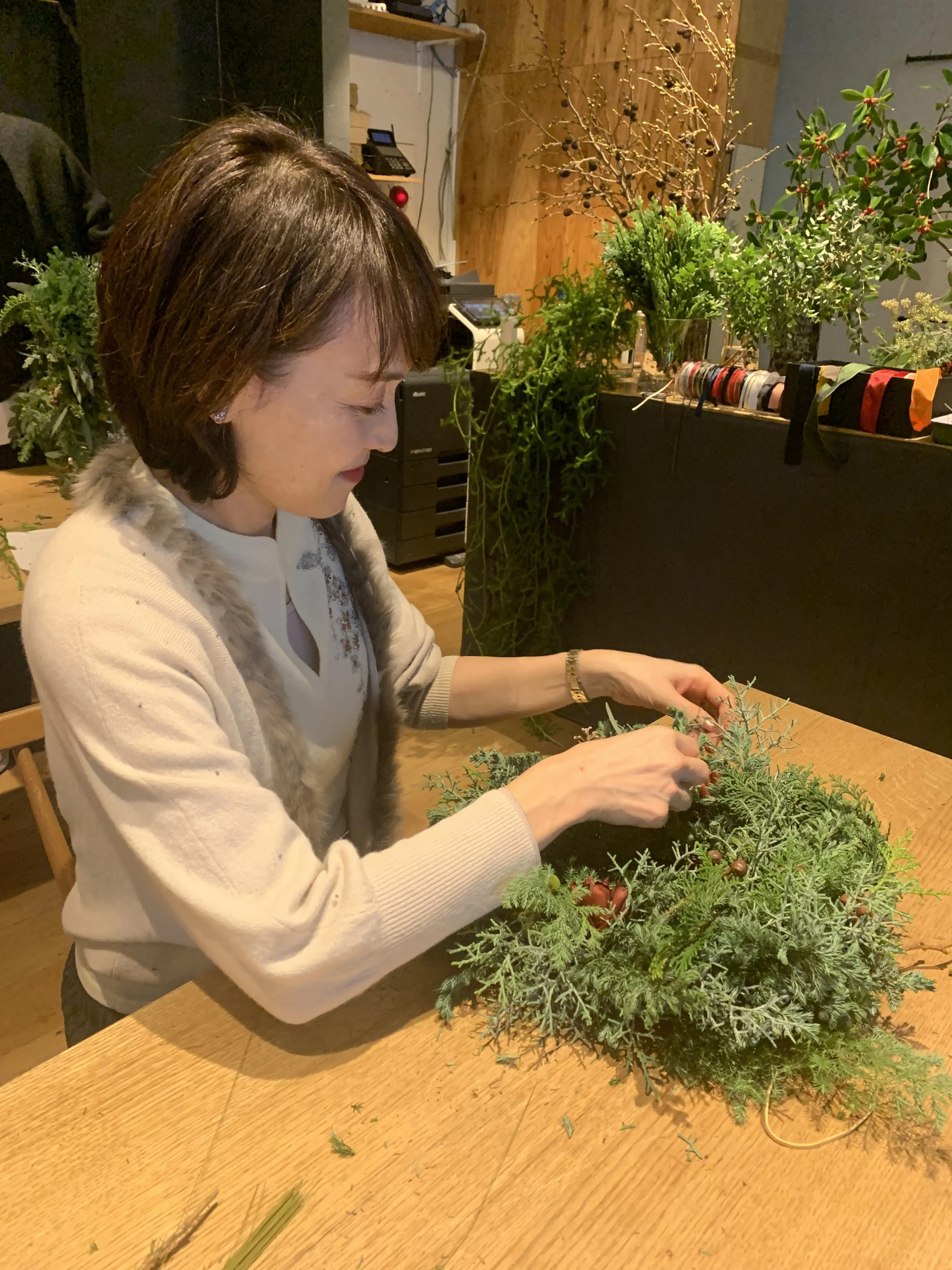 針葉樹を使ったクリスマスリース作りを楽しむ女性