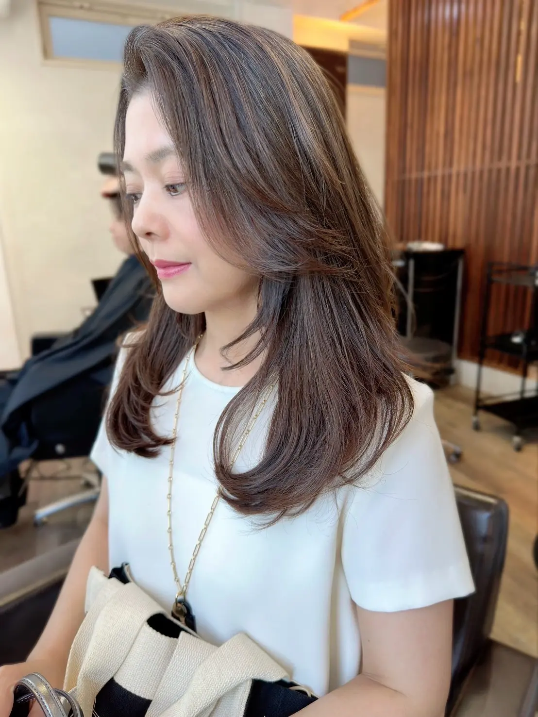 美容院でリタッチしたばかりのロングヘアスタイルの女性。縮毛矯正ヘアでも艶とまとまりのある仕上がりに。