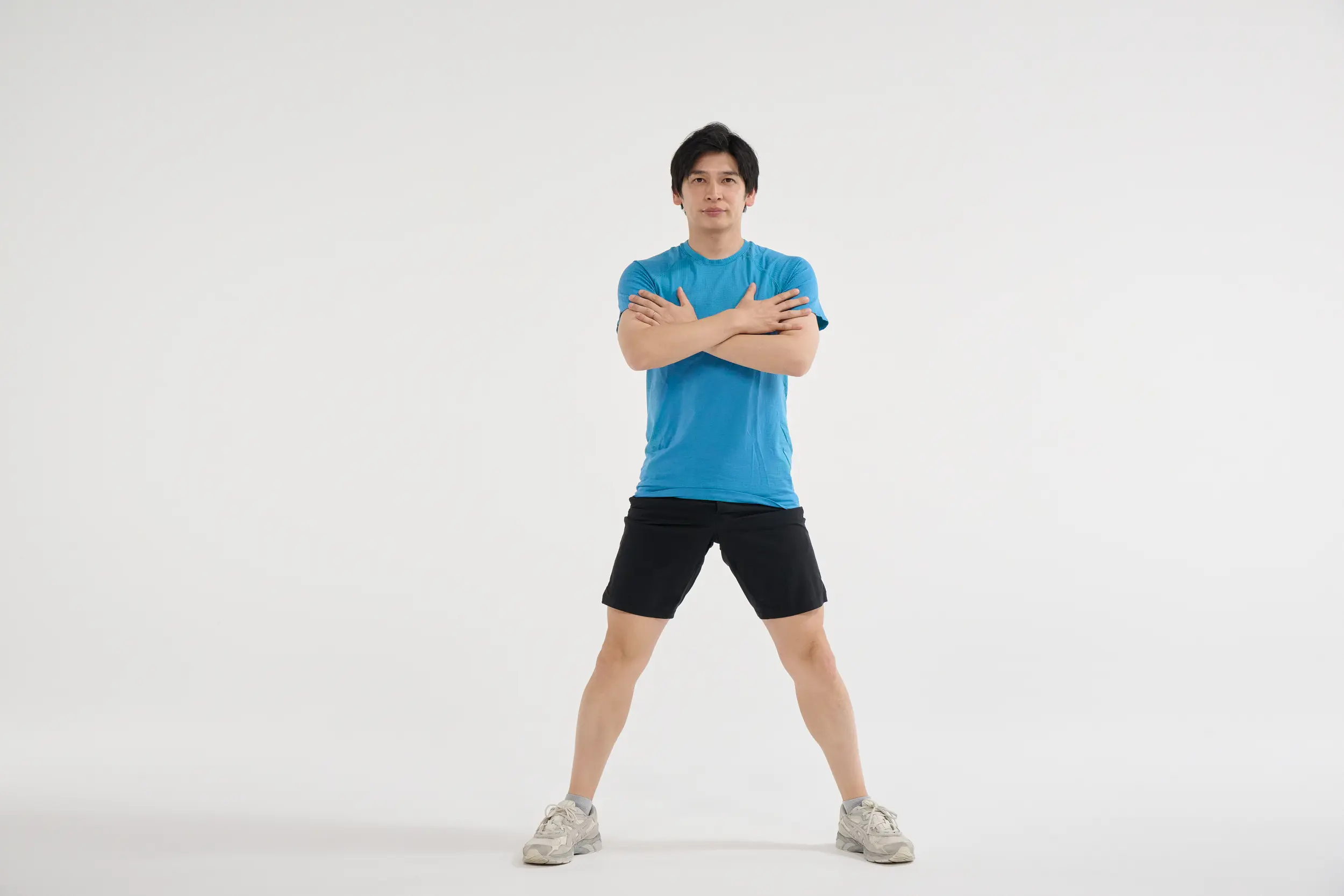 ① 足を肩幅より広めに開き、つま先を30度程外側に向けて、少し膝を曲げる。このとき膝のお皿の中心が小指側を向くようにする。腕は胸の前でクロスさせる。