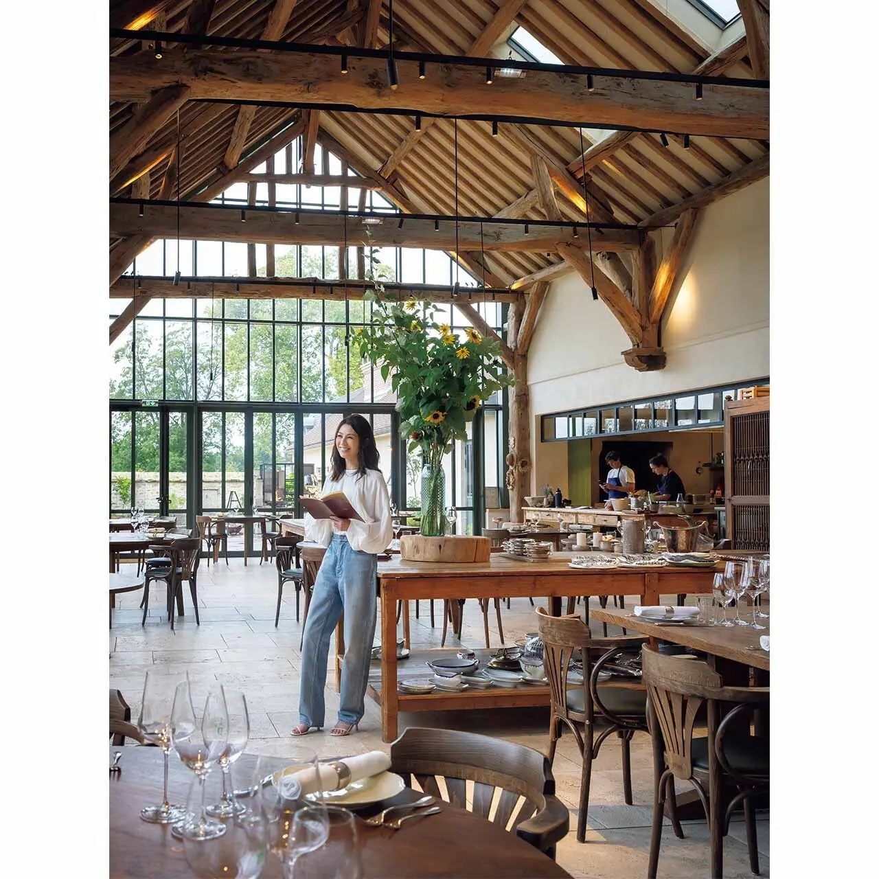 さまざまな木の質感が心地よく、窓の外に農園の緑 が広がるレストラン空間での雨宮さん。このシーン に選んだブラウスとジーンズはともにセリーヌ