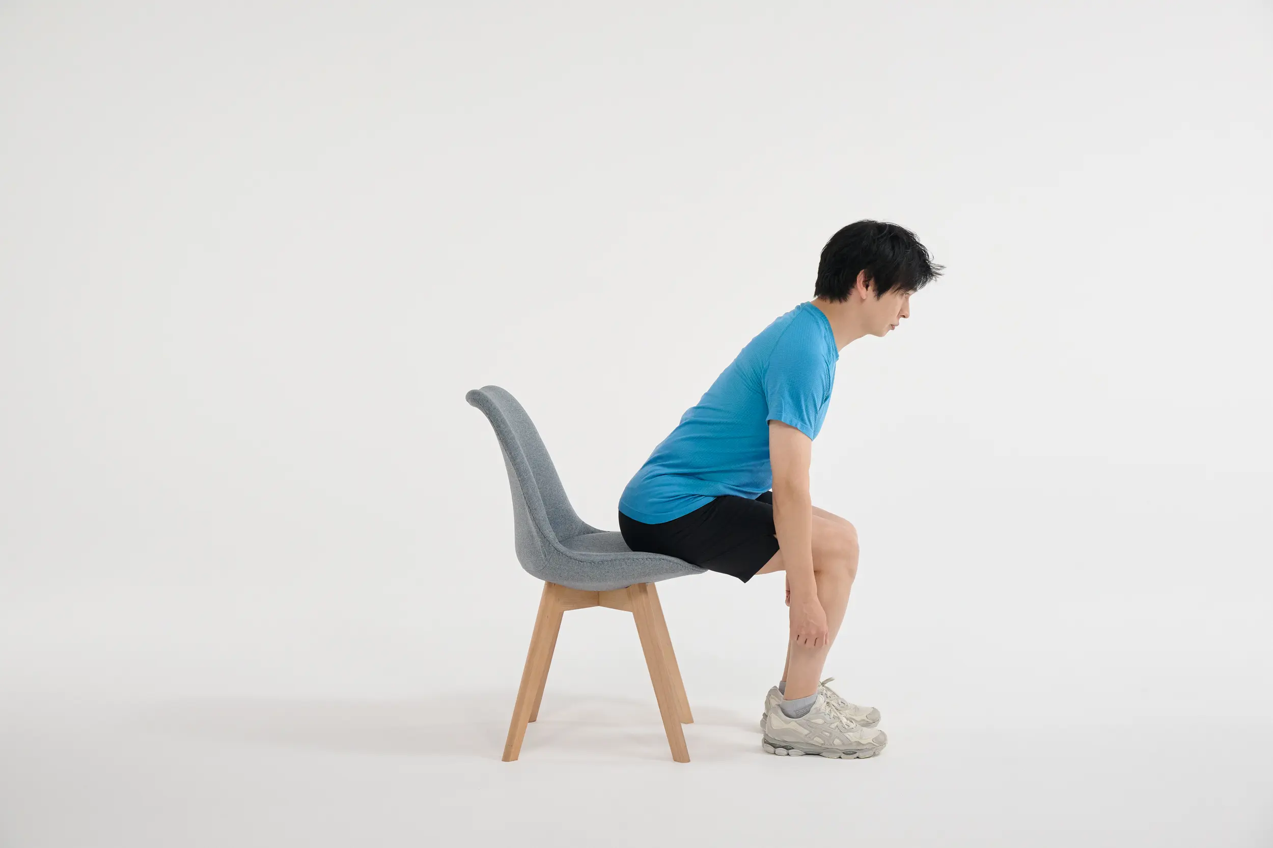 ① 椅子に浅く腰掛け、左右の足はこぶし１個分ほど開き、上体を前に倒す。腕はまっすぐ下ろす。このとき頭から骨盤までが一直線になるように意識する。