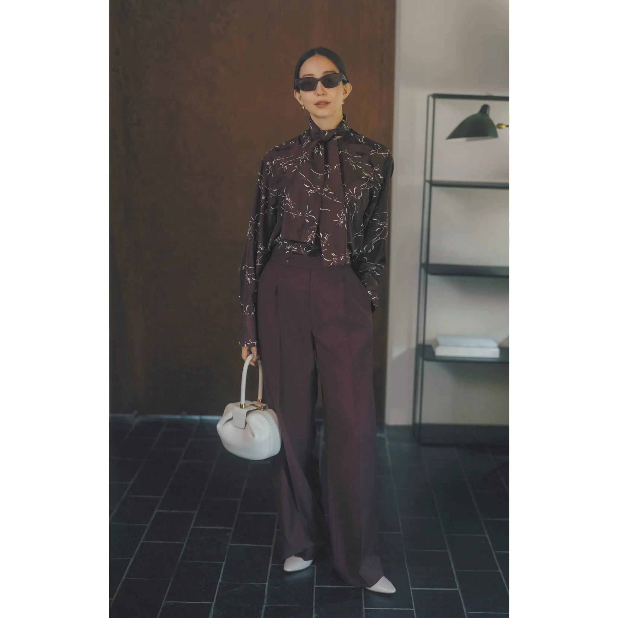 ブラウンに白の花柄がプリントされたボウタイブラウスにブラウンタックパンツを合わせたコーディネート　モデル・松島花