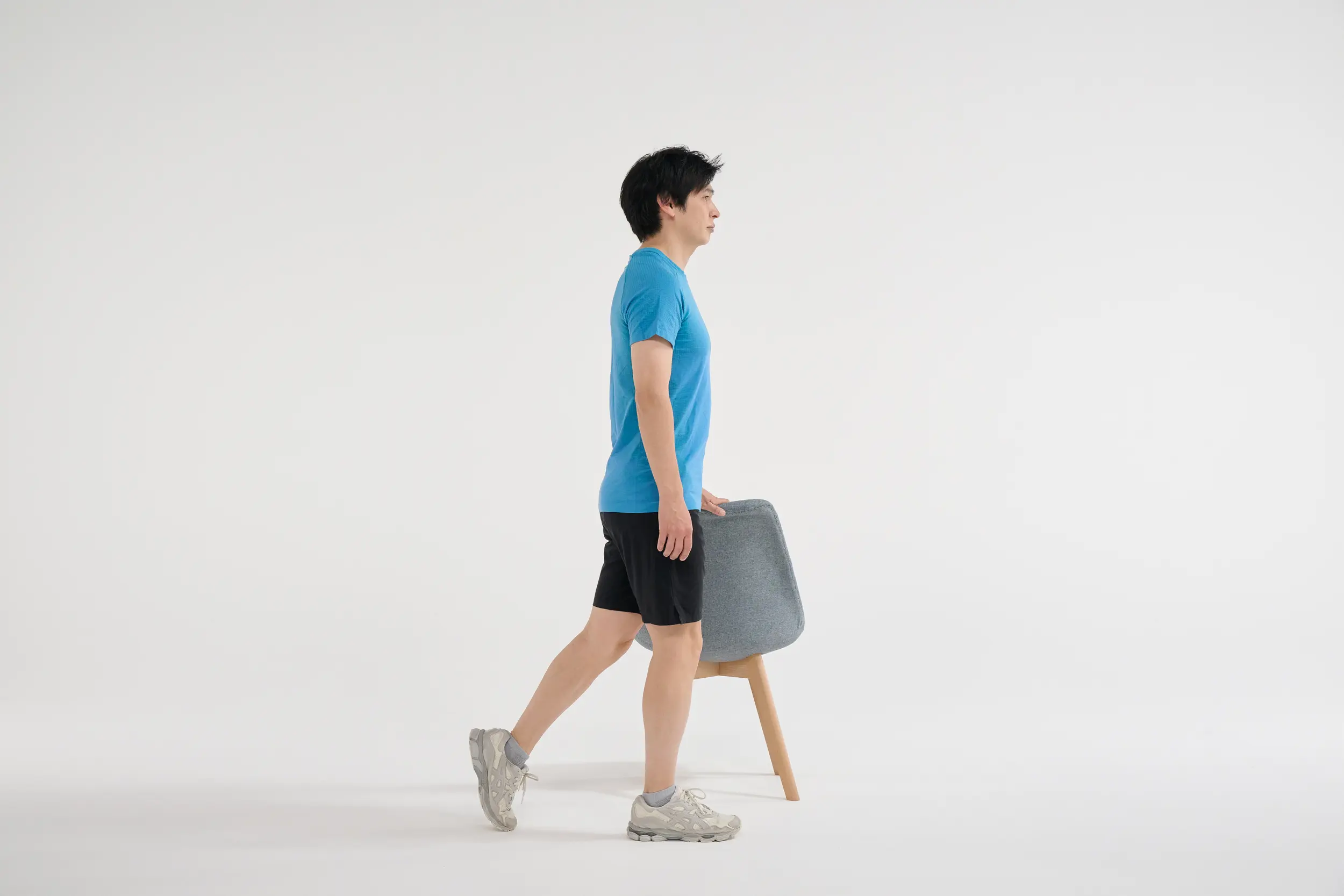 ① 椅子の右側に立ち、左手を椅子の背に置いて体を支え、左脚を後ろに引く。右足の膝のお皿とつま先はまっすぐ前に向ける。