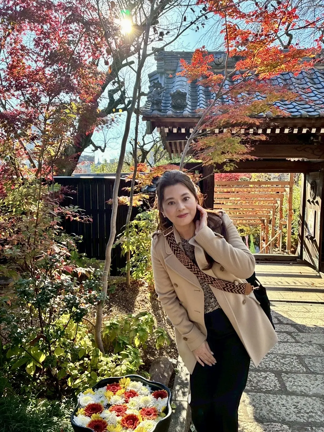 早稲田・法輪寺の紅葉の境内で花手水を背景に撮影した女性の写真。秋の散歩、早稲田さんぽ、花手水が美しい寺院のフォトスポット