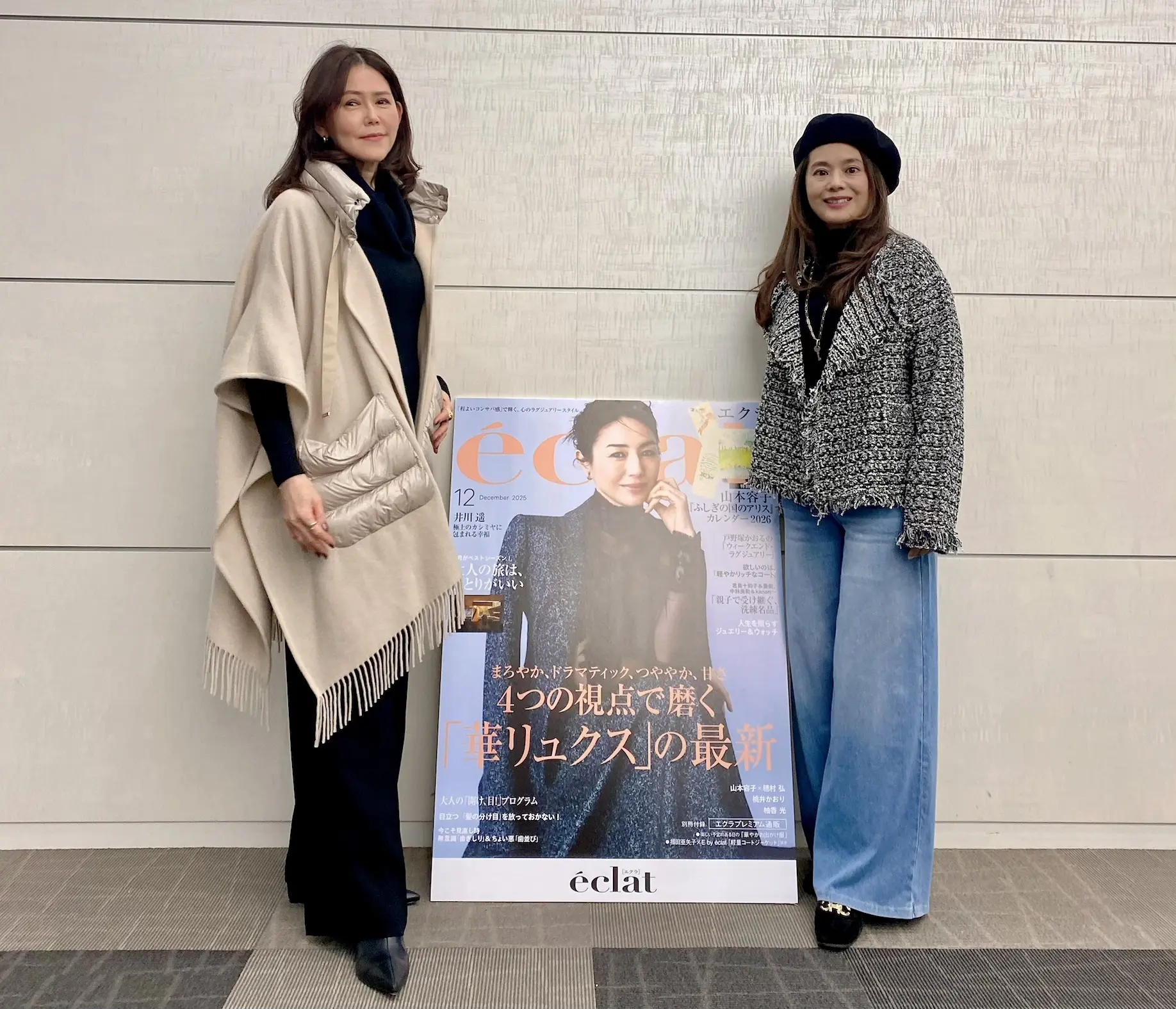 エクラ12月号の表紙パネル前でツーショットに収まるJマダム2人。ベージュの「ヘルノ」ストールコートと「エクラプレミアム」黒のツイードジャケットスタイル。