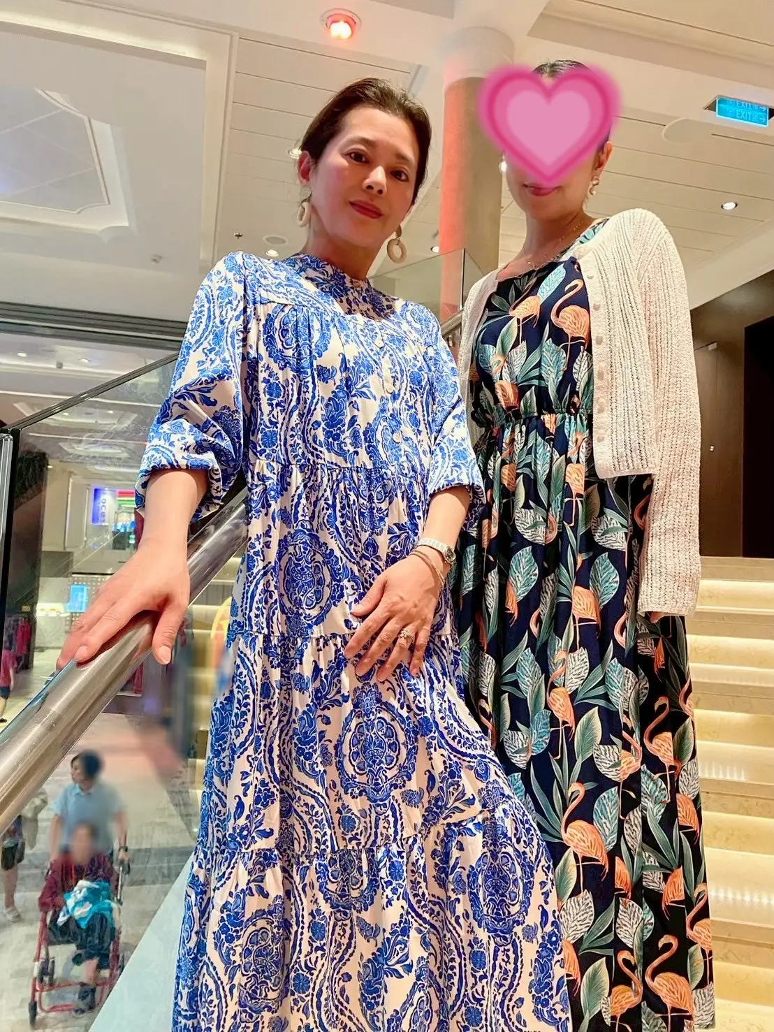 クルーズ船の階段で柄ワンピースを着たポーズをとる二人の女性。