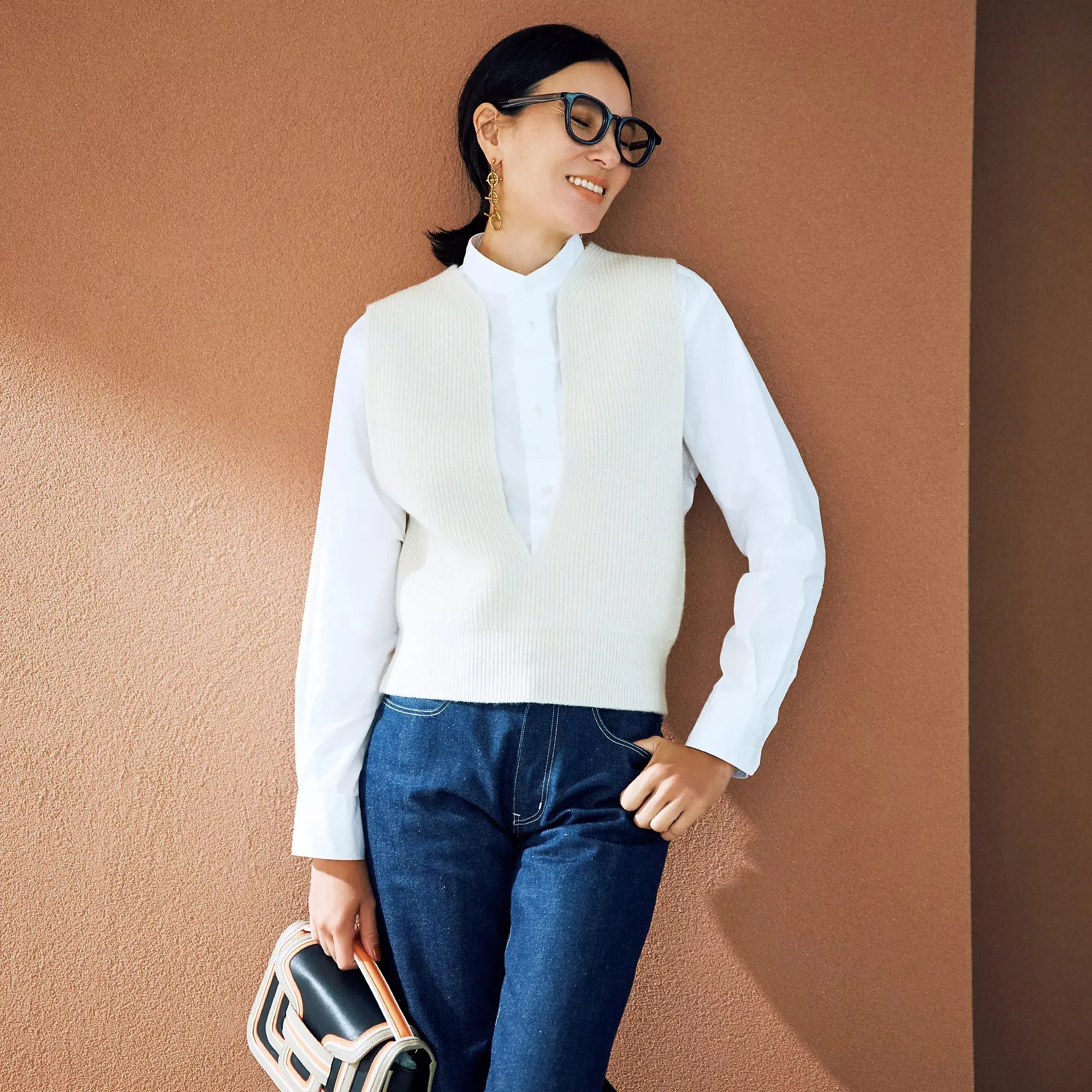 胸元の深いスリットデザインがニットベスト×シャツの装いにスタイリッシュな印象