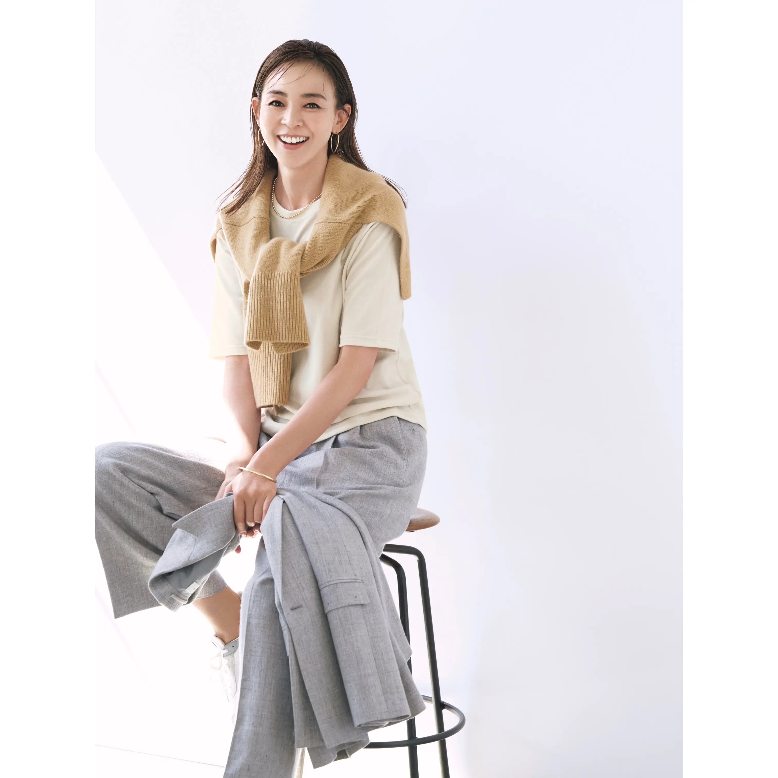 ベージュTシャツにベージュニットを肩がけし、グレーパンツとグレージャケットのセットアップを合わせたコーデ モデル・SHIHO