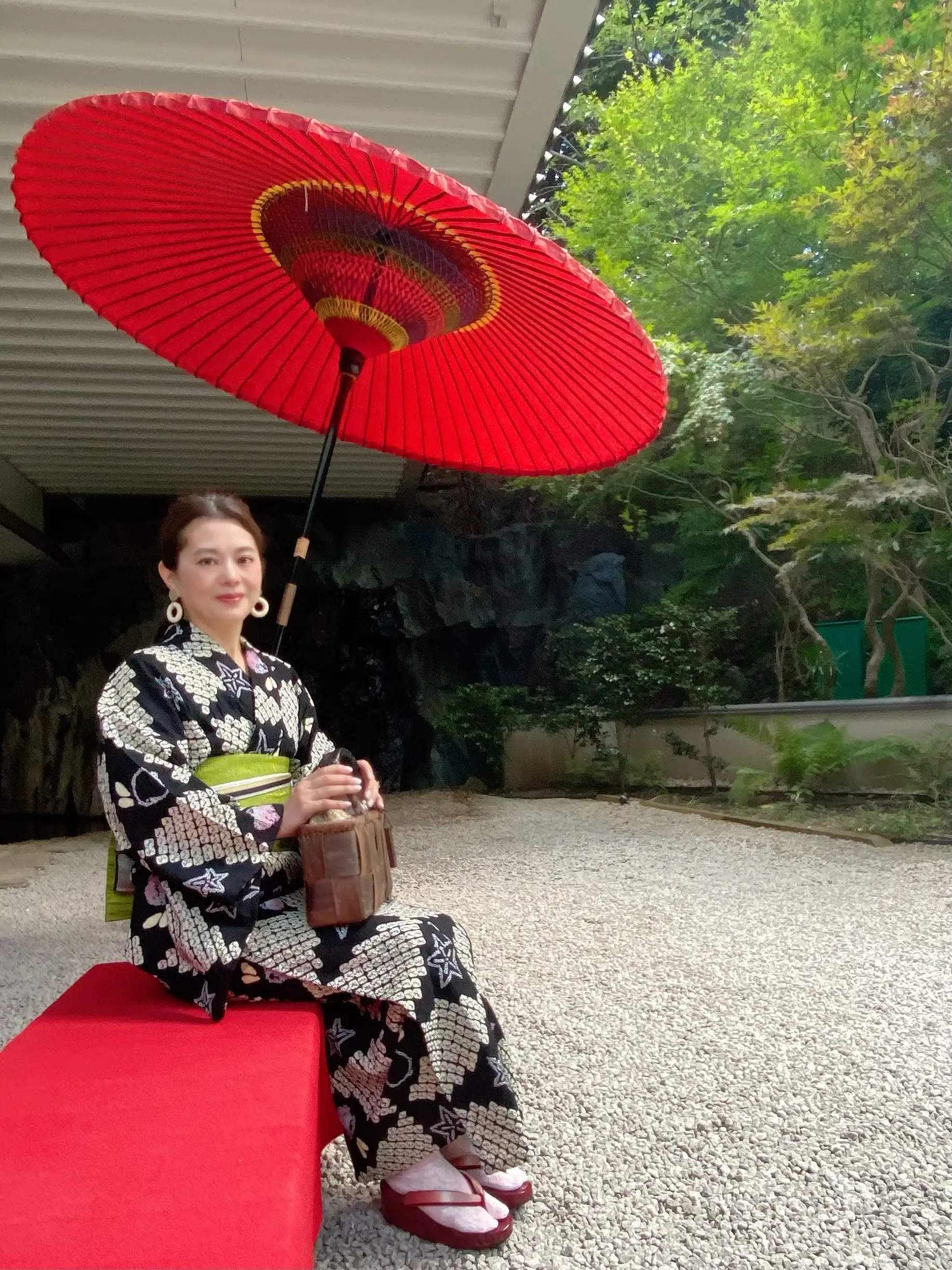 雅叙園の中庭の赤い番傘と浴衣姿の女性。