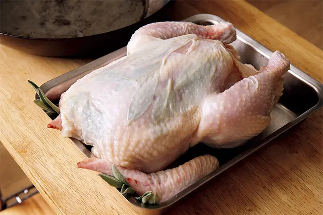 丸鶏はしっかり塩をして、ひと晩おいて 余分な水分を抜く。その後、セージの葉 を入れる。
