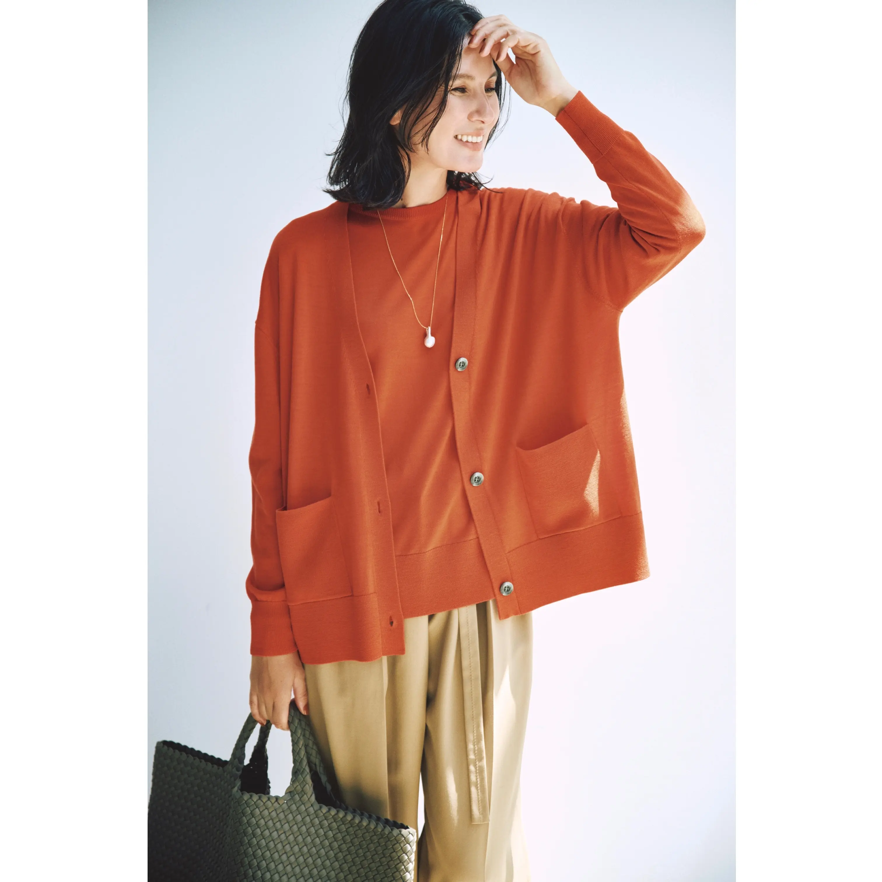 オレンジのツインニットにベージュタックパンツを合わせたコーディネート　モデル・田沢美亜