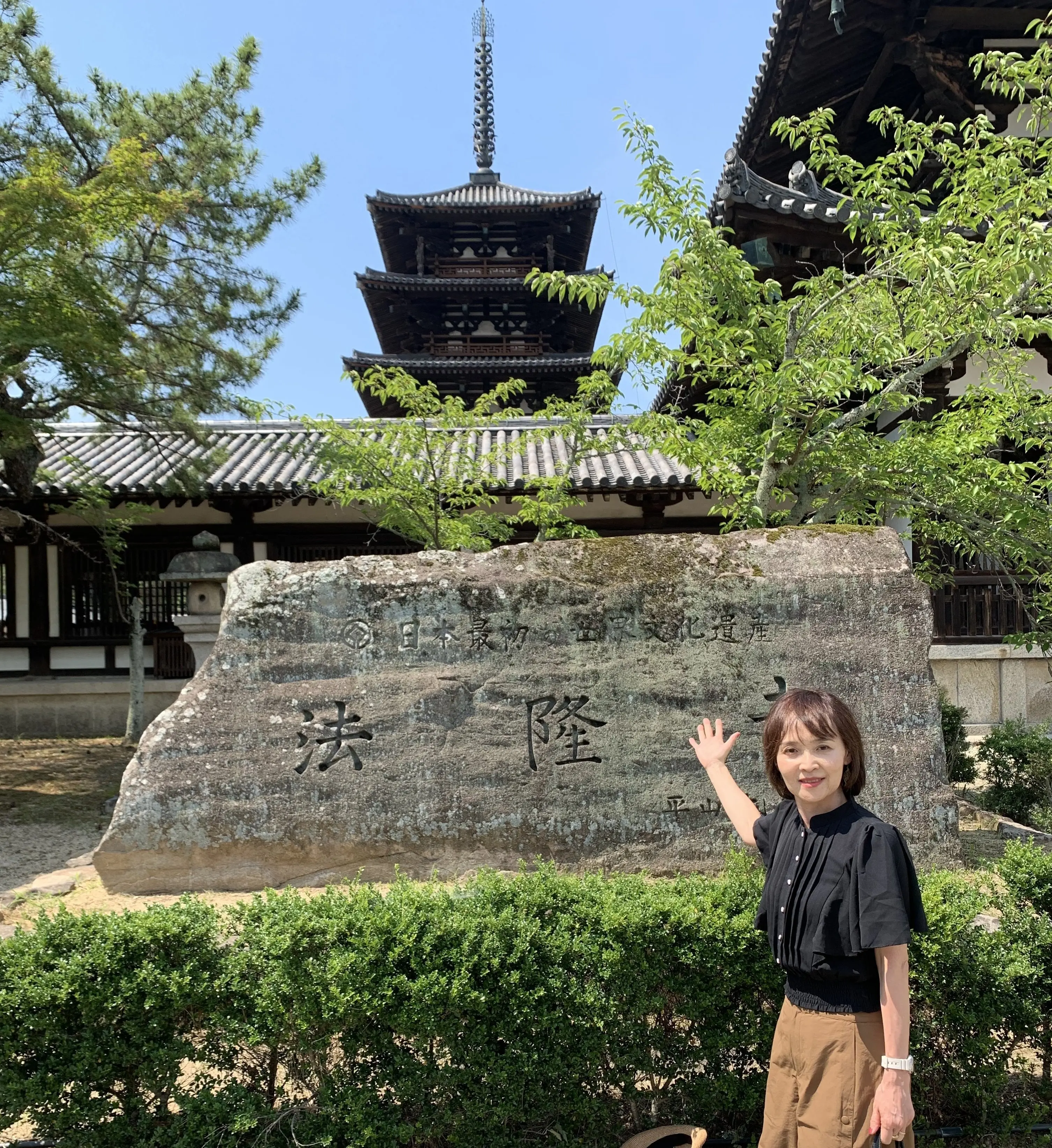 法隆寺の　五重塔をバックに世界遺産登録記念碑の前で写真を撮る女性