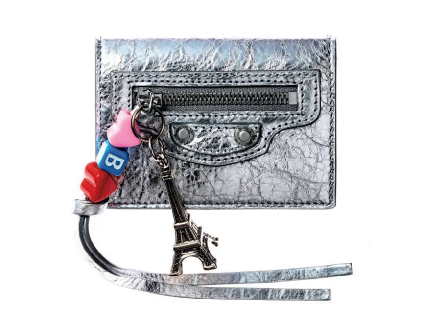 スタイリッシュなシルバーの三つ折り財布にチャームをプラス。ラグジュアリーな今どき感を手に入れて。札入れ1、カード挿し3、ポケット1。  三つ折りウォレット（7×10×4）￥102,300（予定価格）／バレンシアガ クライアントサービス（バレンシアガ）