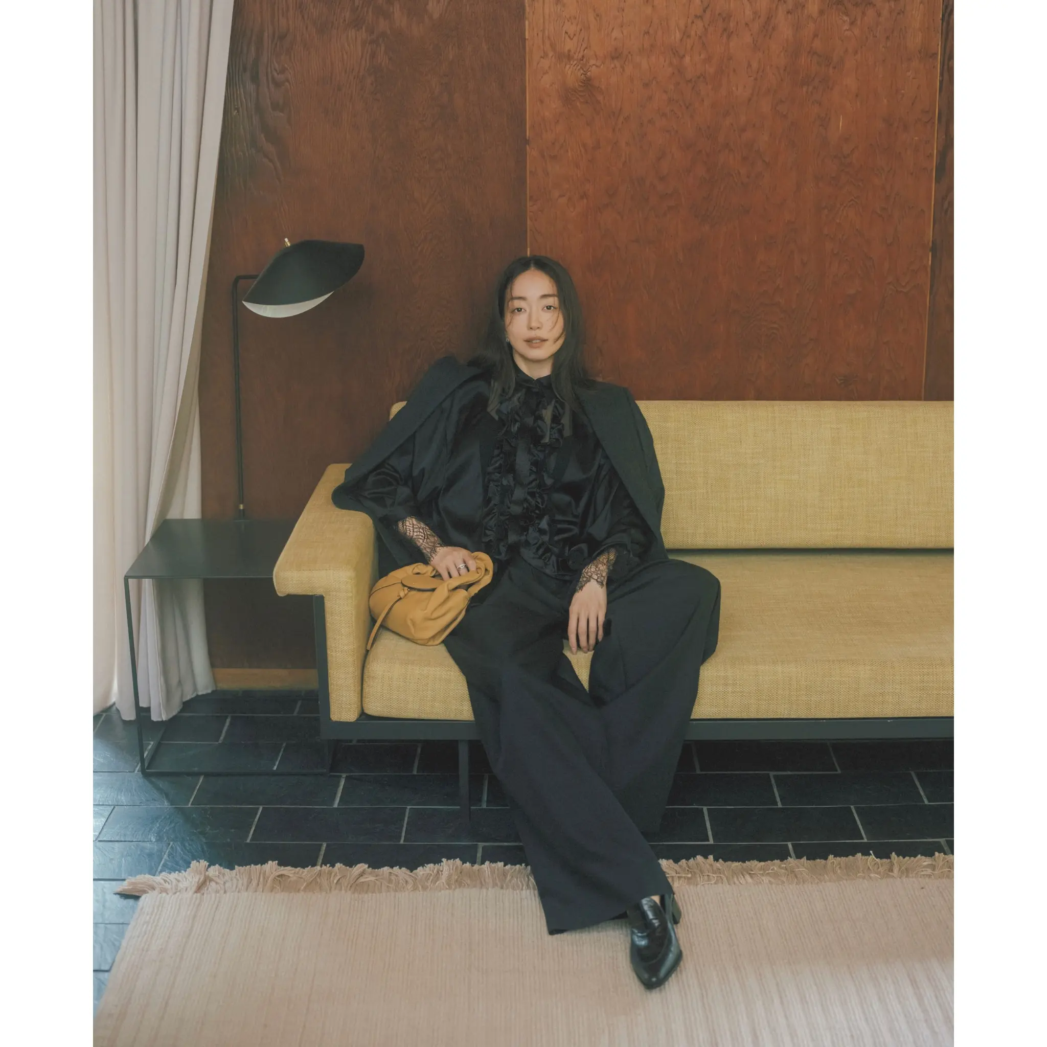 黒フリルつきサテンブラウスに黒ジャケットとパンツを合わせたコーディネート　モデル・松島花