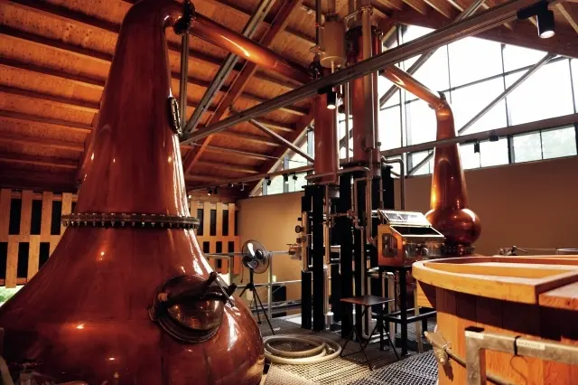 発酵は木桶で、蒸溜釜はストレートネック型（手前）、バルジ型（奥）2機を使い分ける