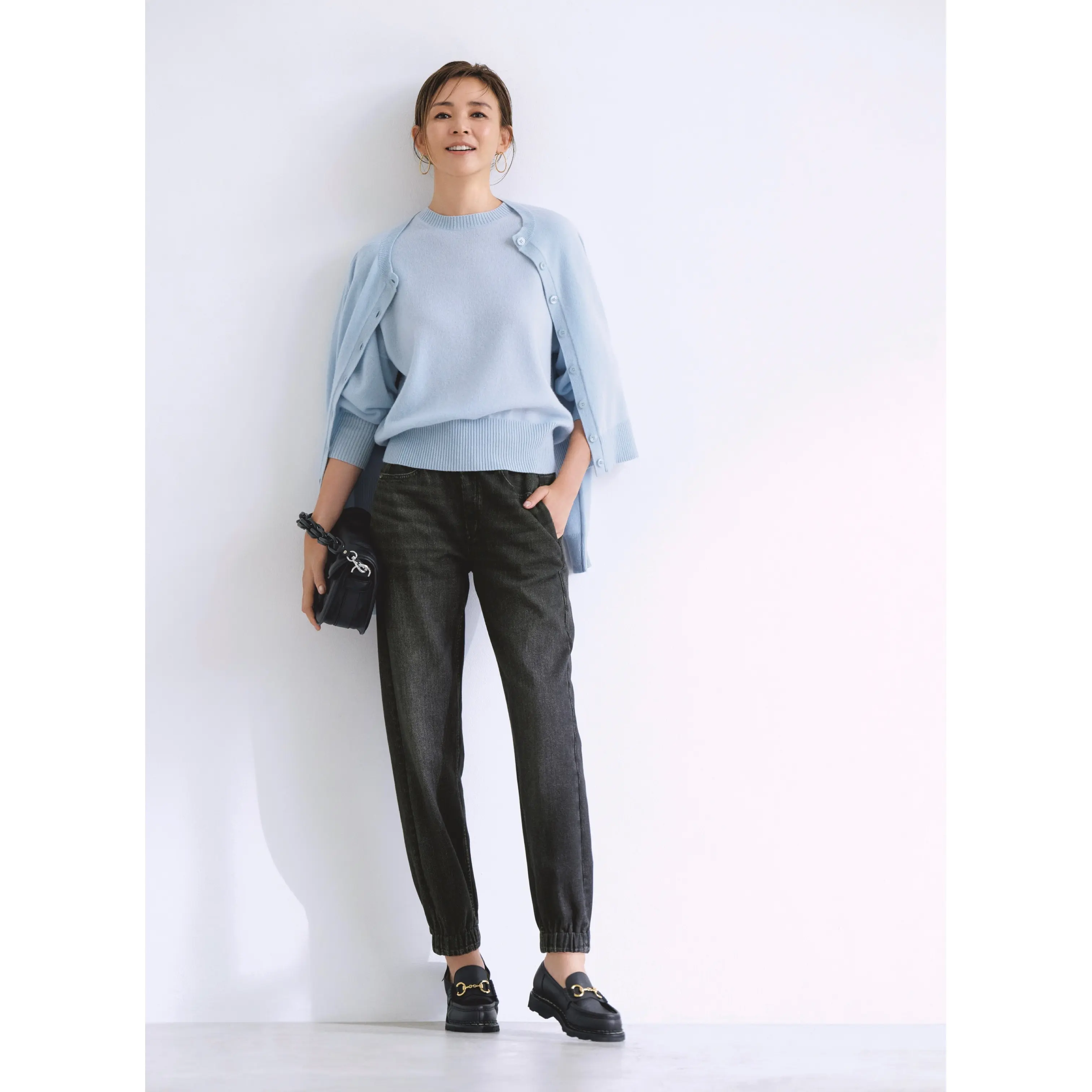 ペールブルーのニットトップスとカーディガンに黒デニム風パンツを合わせたコーディネート モデル・SHIHO