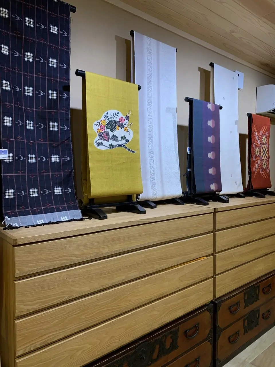 左側から琉球絣の反物、琉球紅型の名古屋帯、結城紬の反物、諸紙布の名古屋帯、雪姫紬の反物、南風原花織の名古屋帯