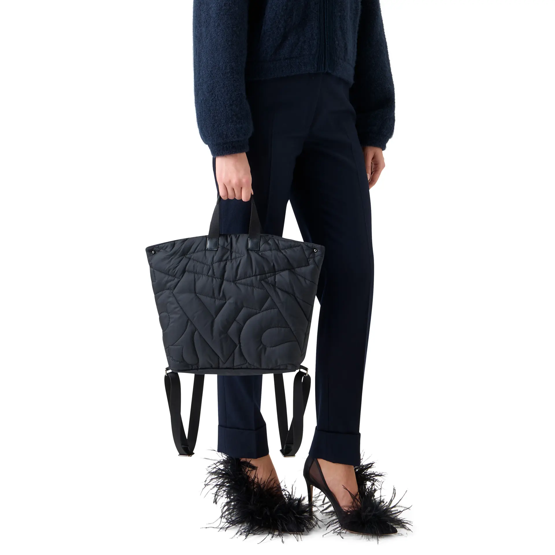 バッグ「アクリス アイ スモールバックパック」を手に持った女性モデル
