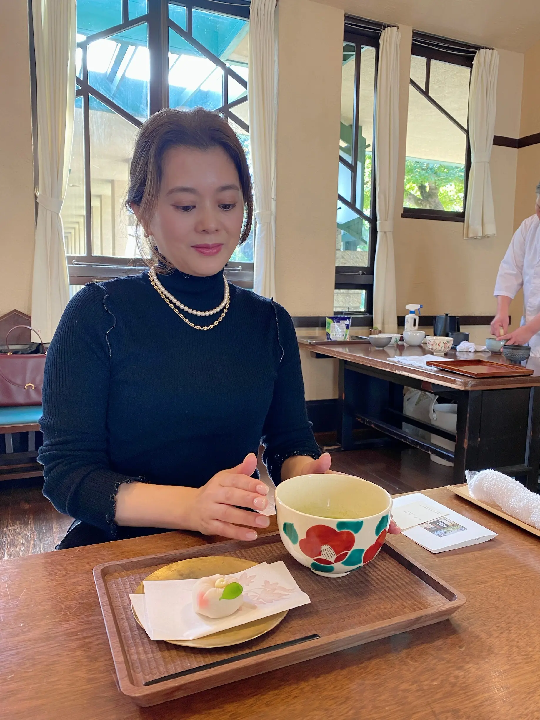 練り切りとお抹茶を前に座る女性（体験者）が微笑んでいる様子。