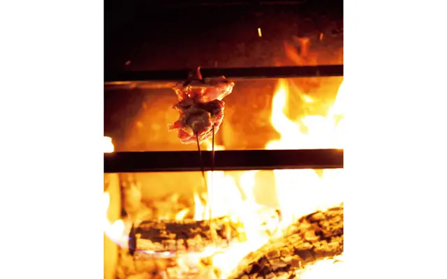 シンプルモダンなカウンターの目の前に薪火が。丸山さんが調理する姿を眺めながらの食事