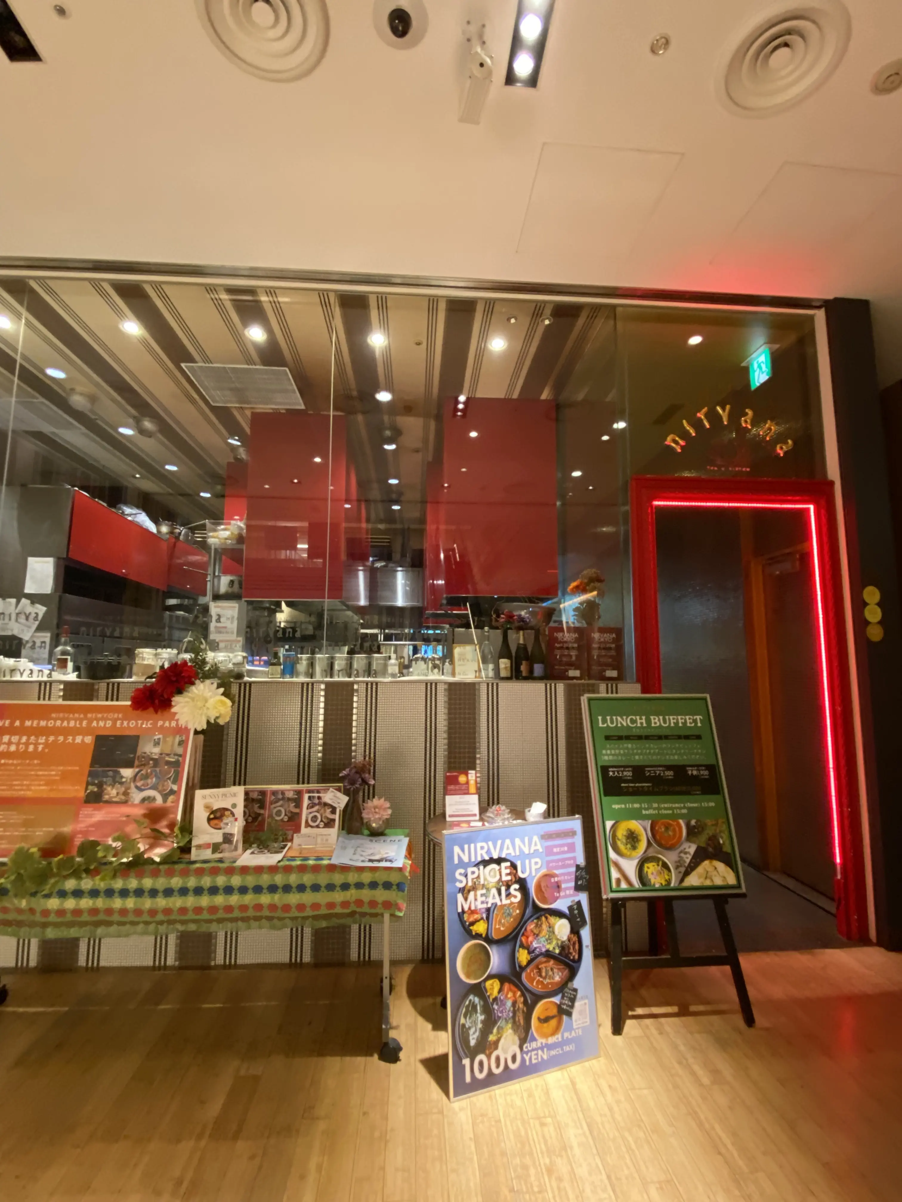 六本木ミッドタウンのインド料理店「ニルヴァーナ・ニューヨーク」の外観。ランチビュッフェやカレーの看板が並ぶ入口の様子。