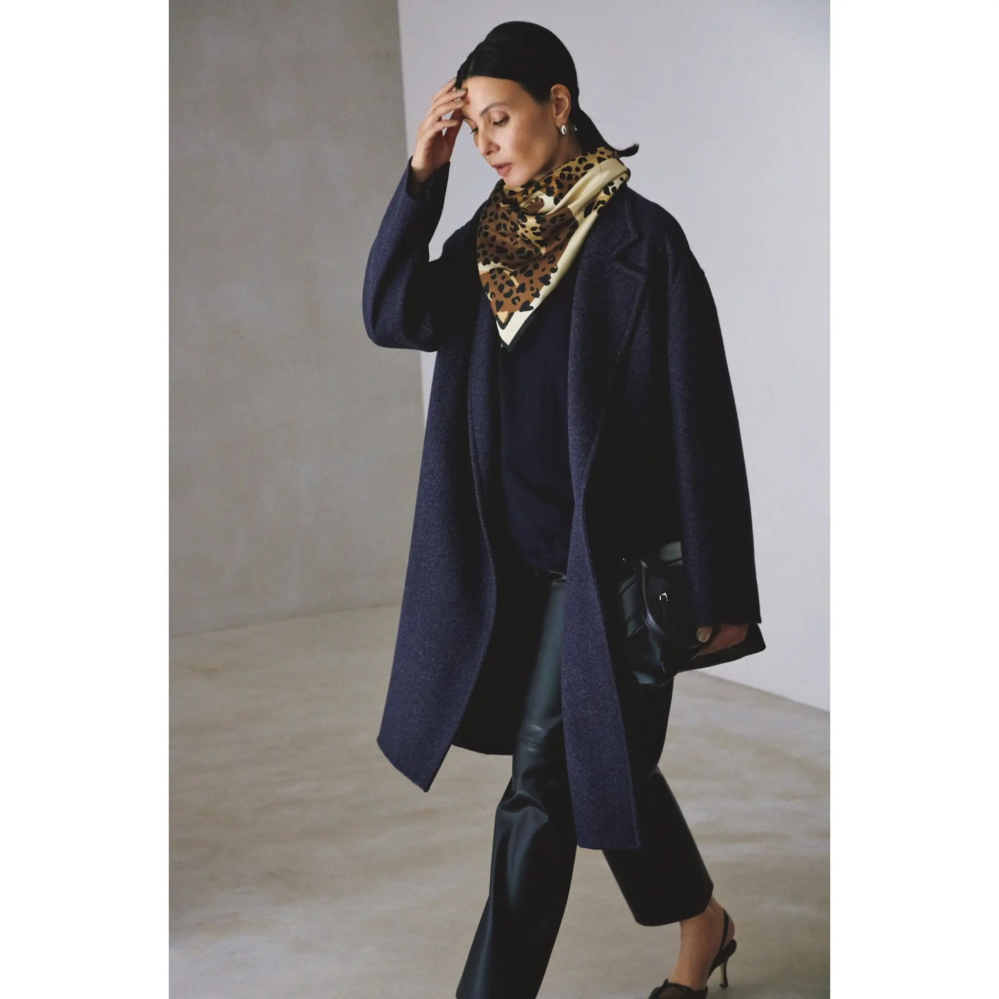 ネイビーのコートとニットを合わせてレオパード柄スカーフを首元に巻き、黒レザーパンツを合わせたコーディネート　モデル・田沢美亜