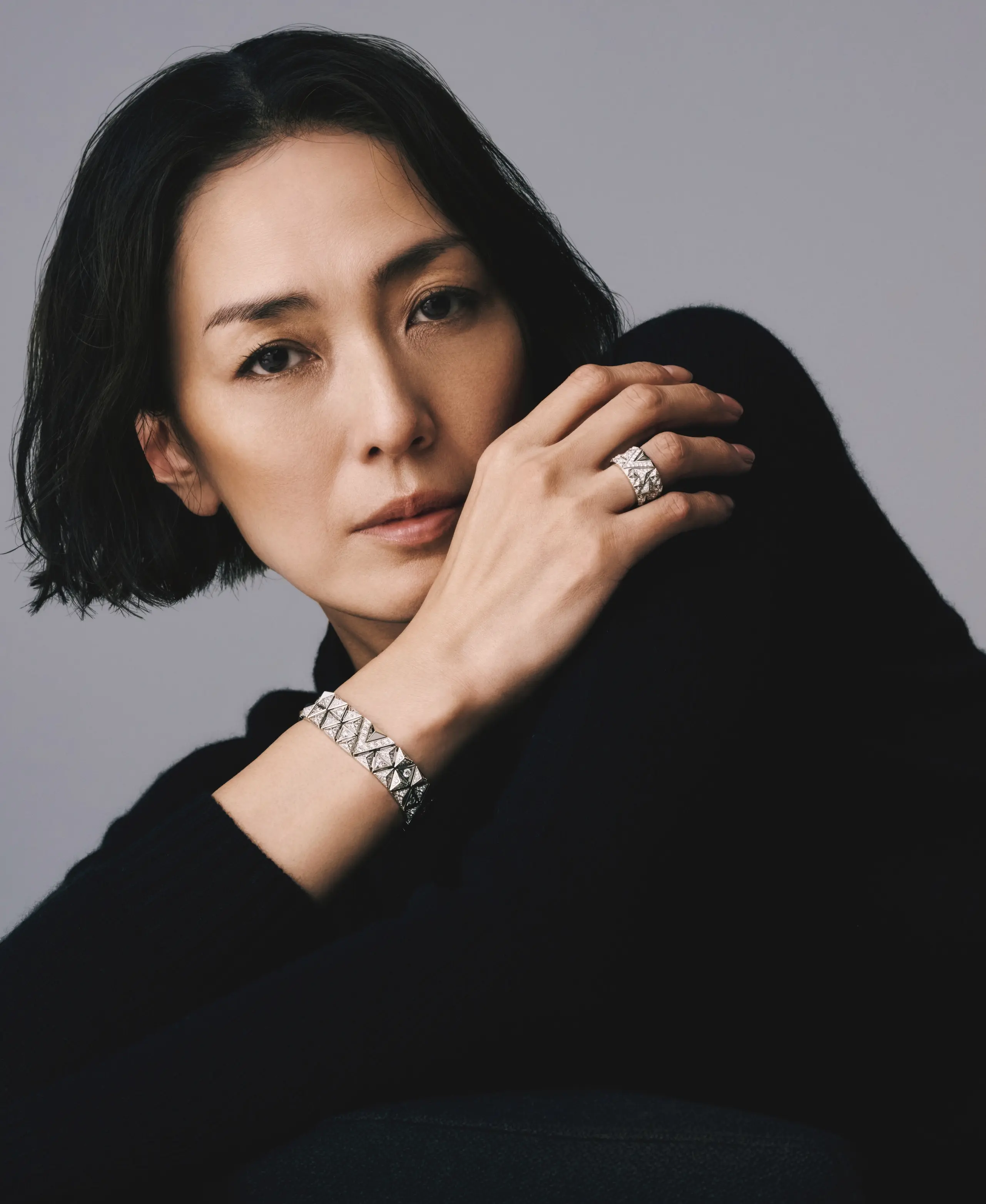 ブラックのクルーネックニットを背景に圧 倒的な存在感を放つコレクション「ピュア V」は、メゾンのイニシャルである「V」モ チーフの現代的な解釈をさらに進化させた もの。線、三角形、ピラミッドのモチーフ が重なり合った格子細工は、その精緻な構 造による驚くべきしなやかさが特徴。細部 にまで宿る精密な職人技が、躍動感、エネ ルギー、リズムを感じさせる逸品ジュエリ ーだ。ジュエリーともに「ピュア V」（WG ×D）リング￥3,960,000・ブレスレット￥ 8,734,000・ニット￥291,500／ルイ･ヴィト ン クライアントサービス（ルイ･ヴィトン）