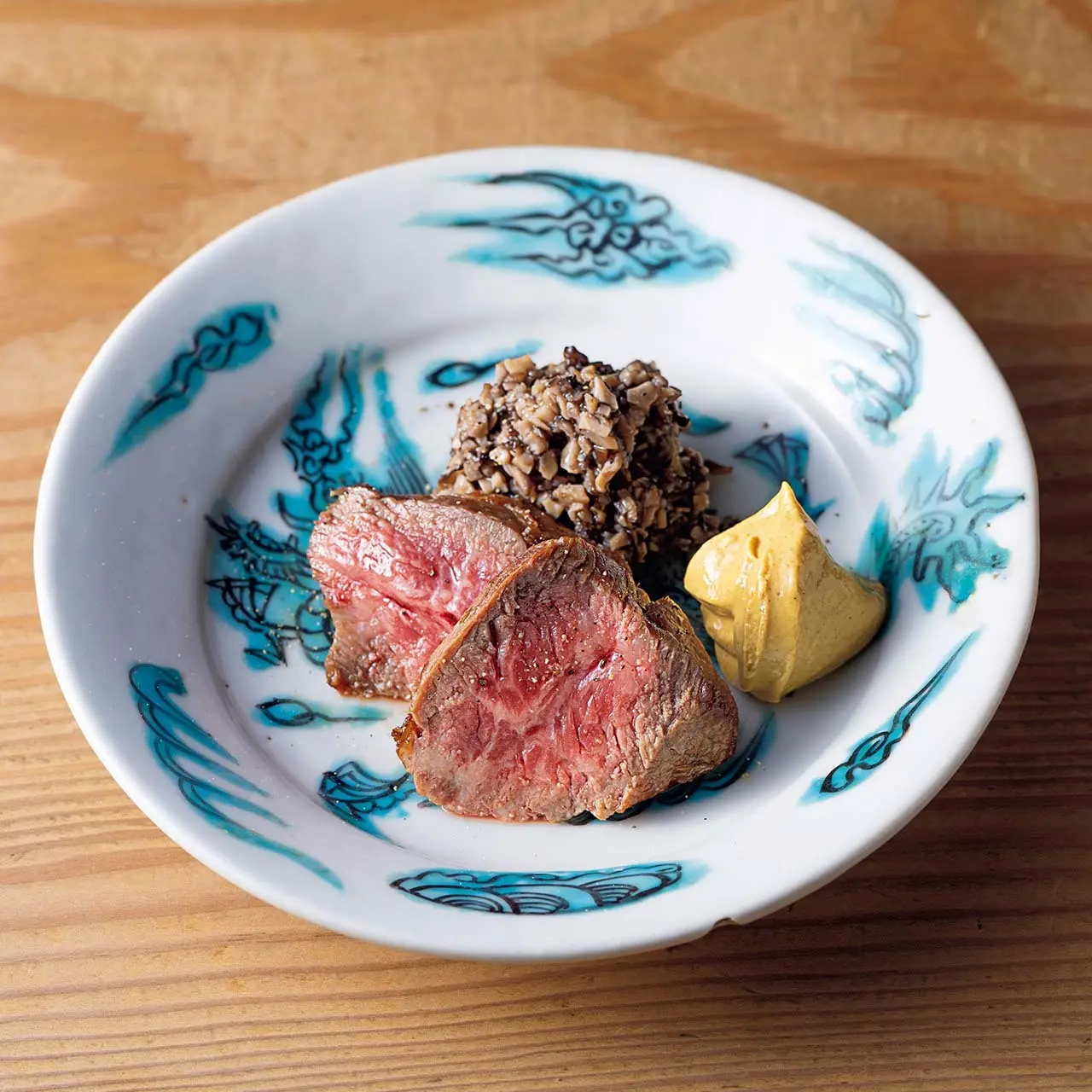 「和牛ラムシンの炭火焼のきの こソース添え」。器は明末期のもの