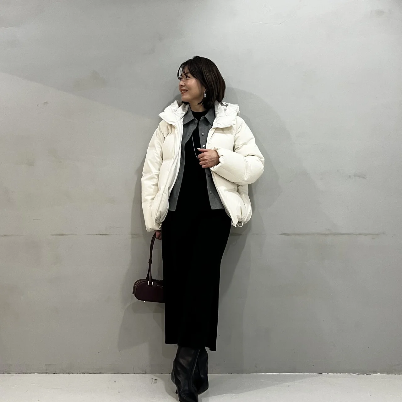 黒いワンピースにツイード風シャツのグレー、白いダウンジャケットを合わせたコーデ