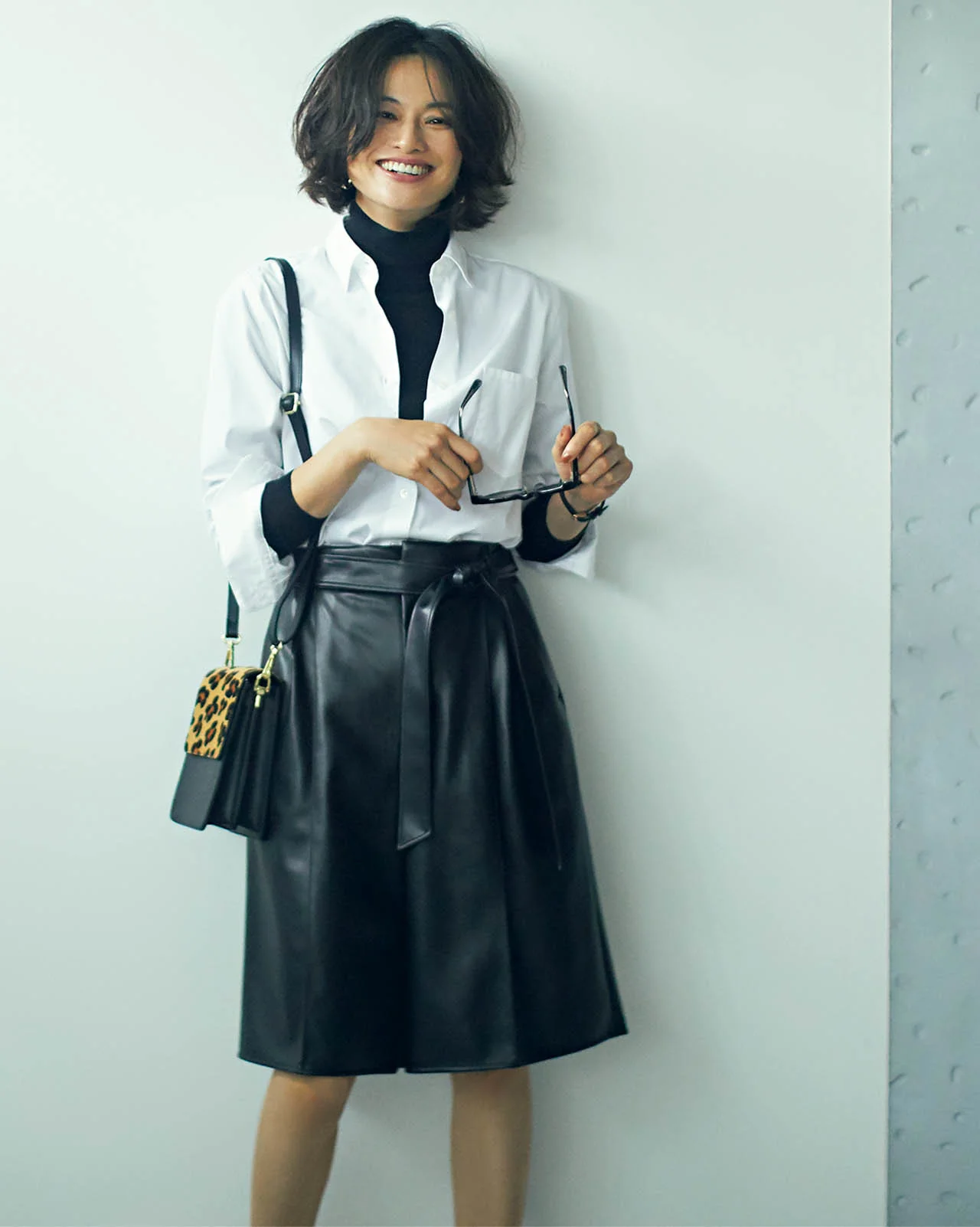 白シャツ×膝丈のレザーハーフパンツコーデを着たモデルの渡辺佳子さん