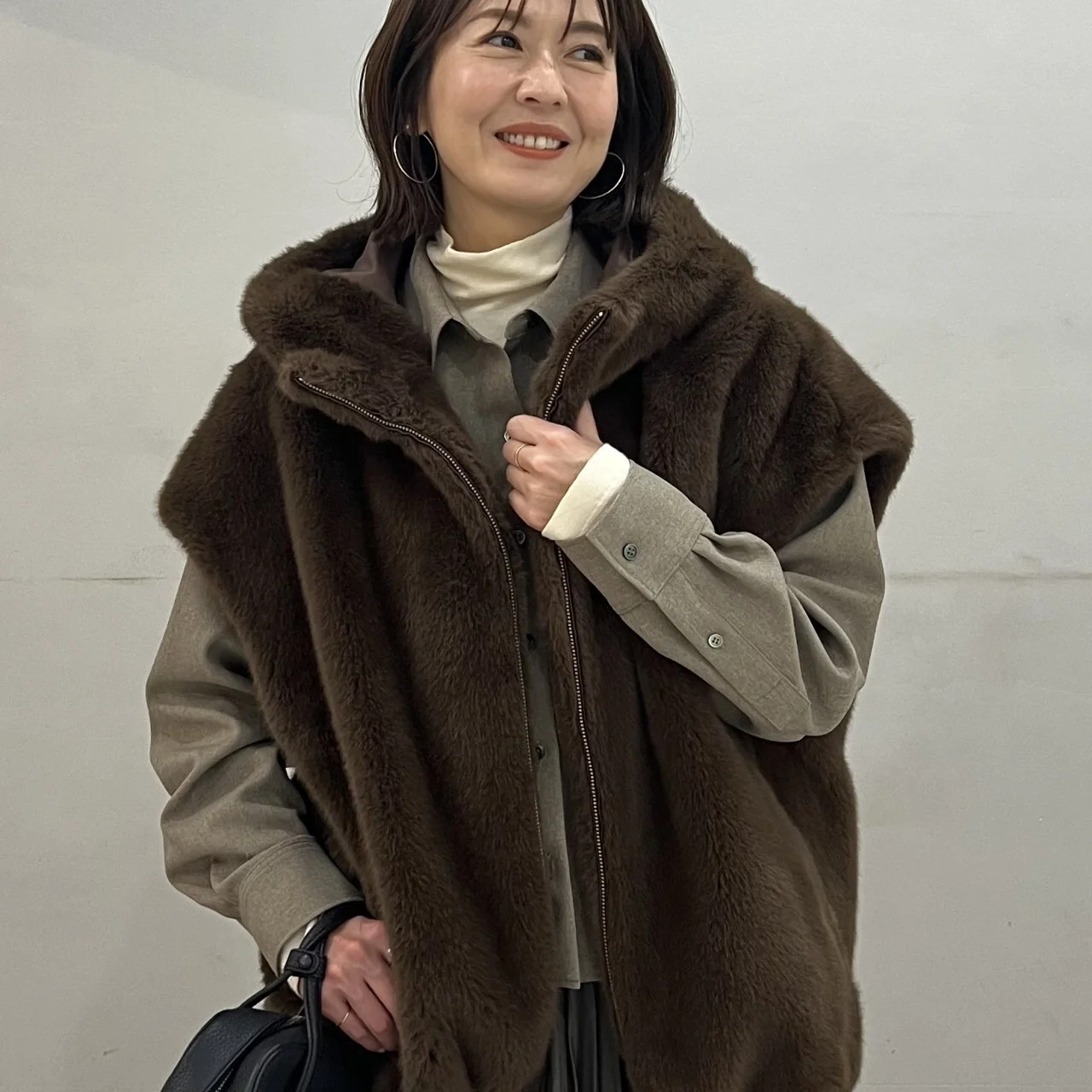 黒いスカートにツイード風シャツのベージュ、ブラウンのファーベストを合わせたコーデ