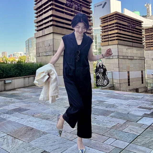 ネイビーのコンビネゾンにアイボリージャケットを羽織った、大人のきれいめモノトーンコーデ。都会に映える、こなれ感あふれる初夏の着こなし。