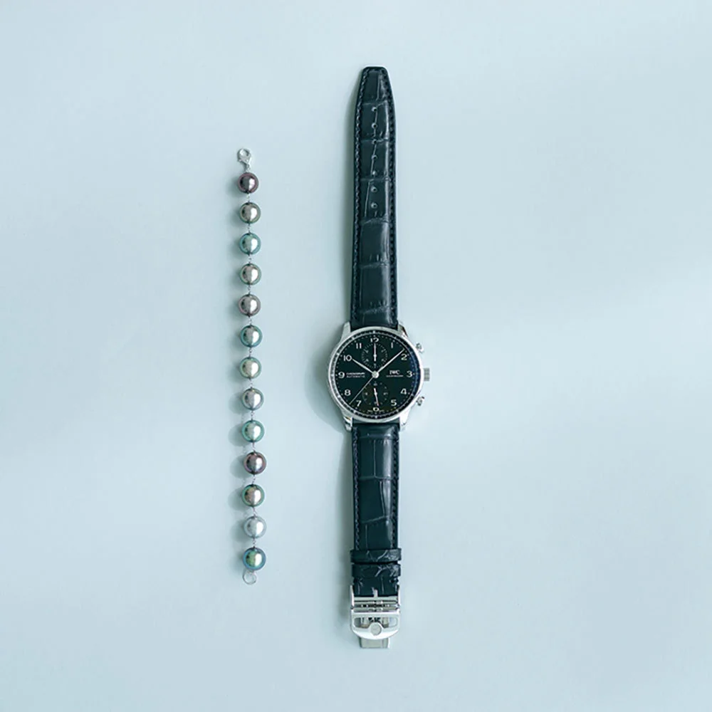 ❶時計「ポルトギーゼ・クロノグラフ」（SS、径41㎜、自動巻き）￥907,500／IWC　❷ブレスレット（WG×黒蝶真珠）￥209,000／キノシタパール