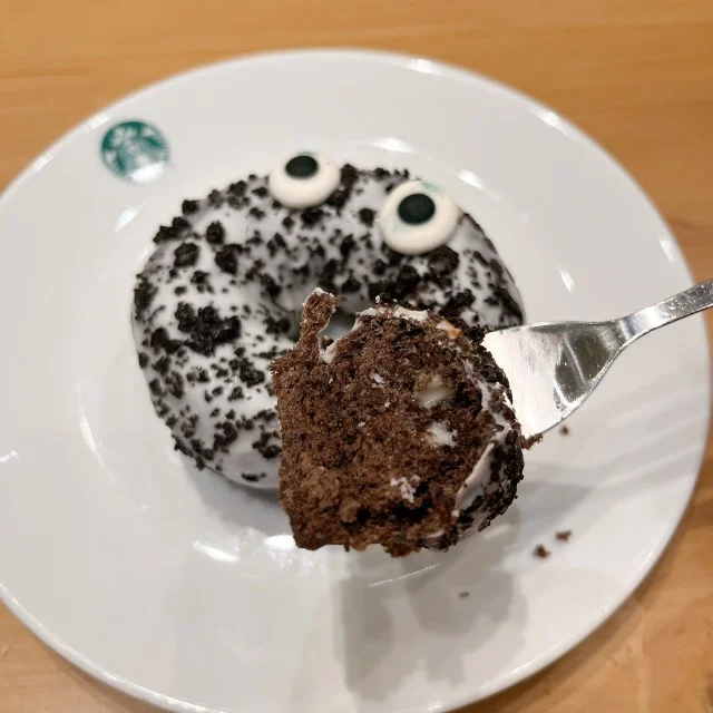 スターバックスのクッキーアンドクリームドーナツをフォークで差している画像