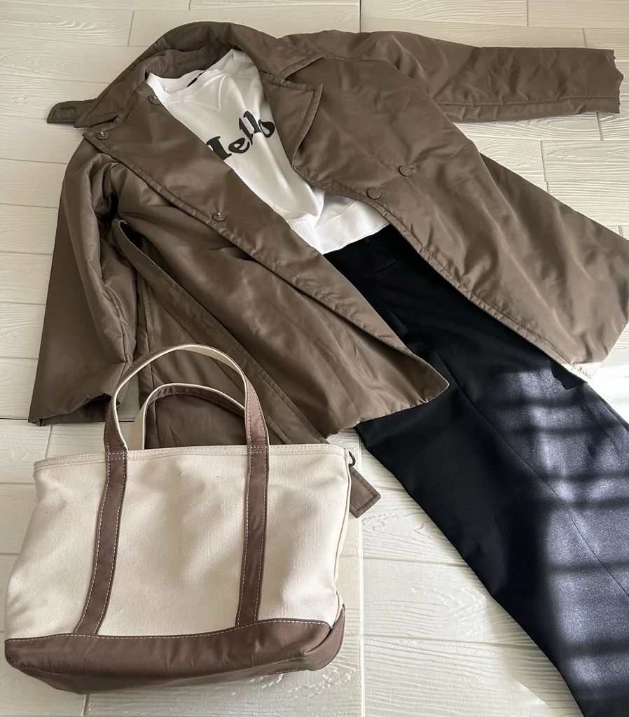 中綿ショートトレンチに白いロゴトップスと黒パンツを合わせたコーデ