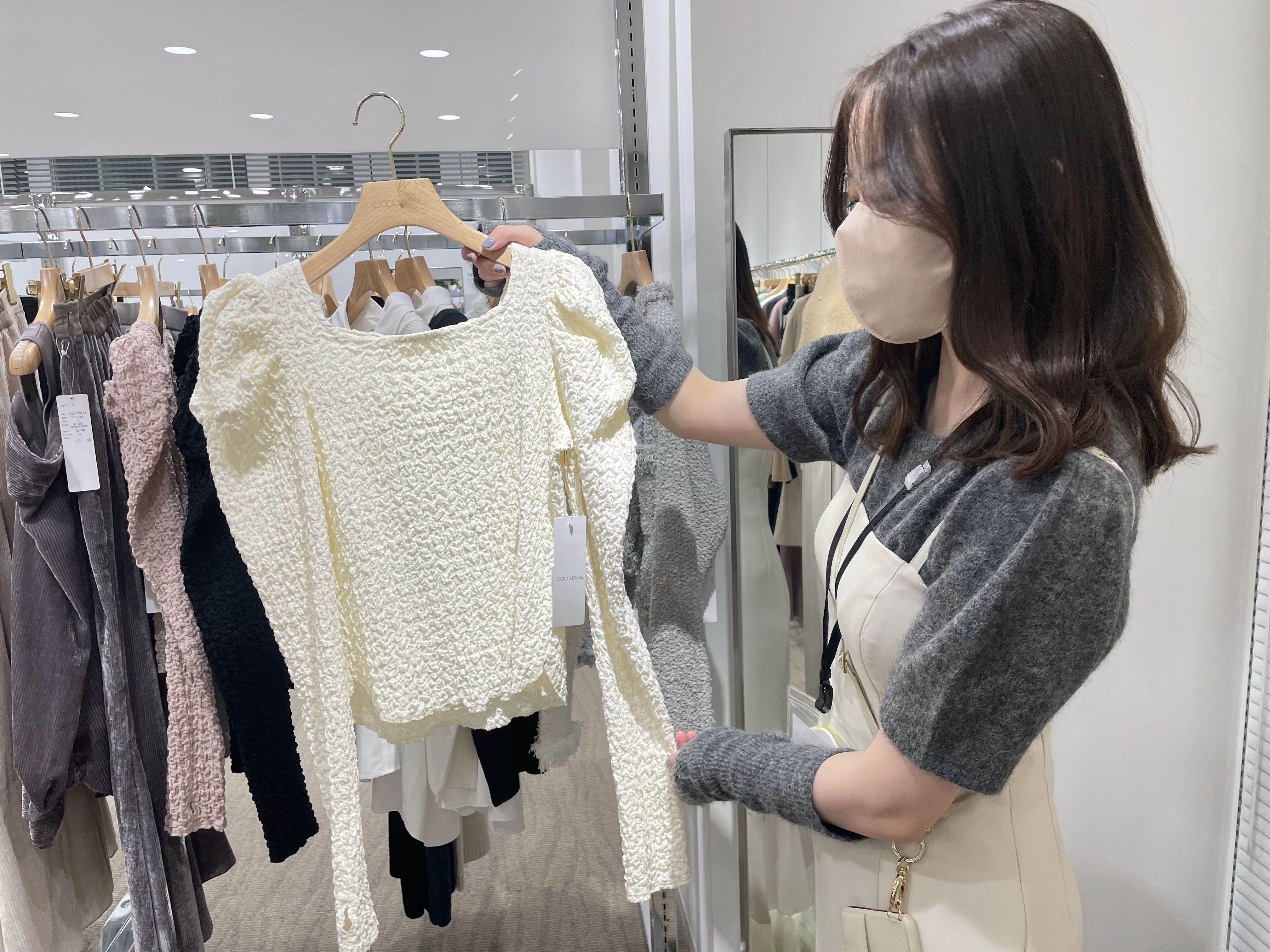 雑誌「non-no」の編集者・廣井さんが、展示会で洋服の肌触りや透け感を確認している写真。