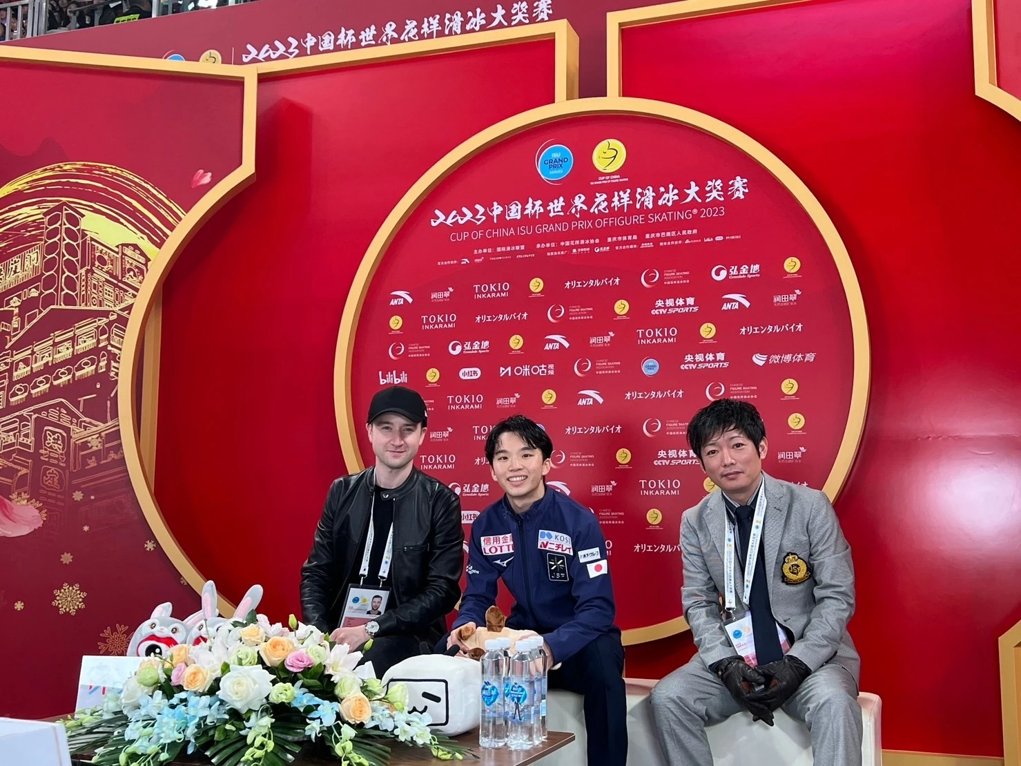 中国杯キスアンドクライに座る友野一希さんと平池大人コーチ、ミーシャ・ジーさん