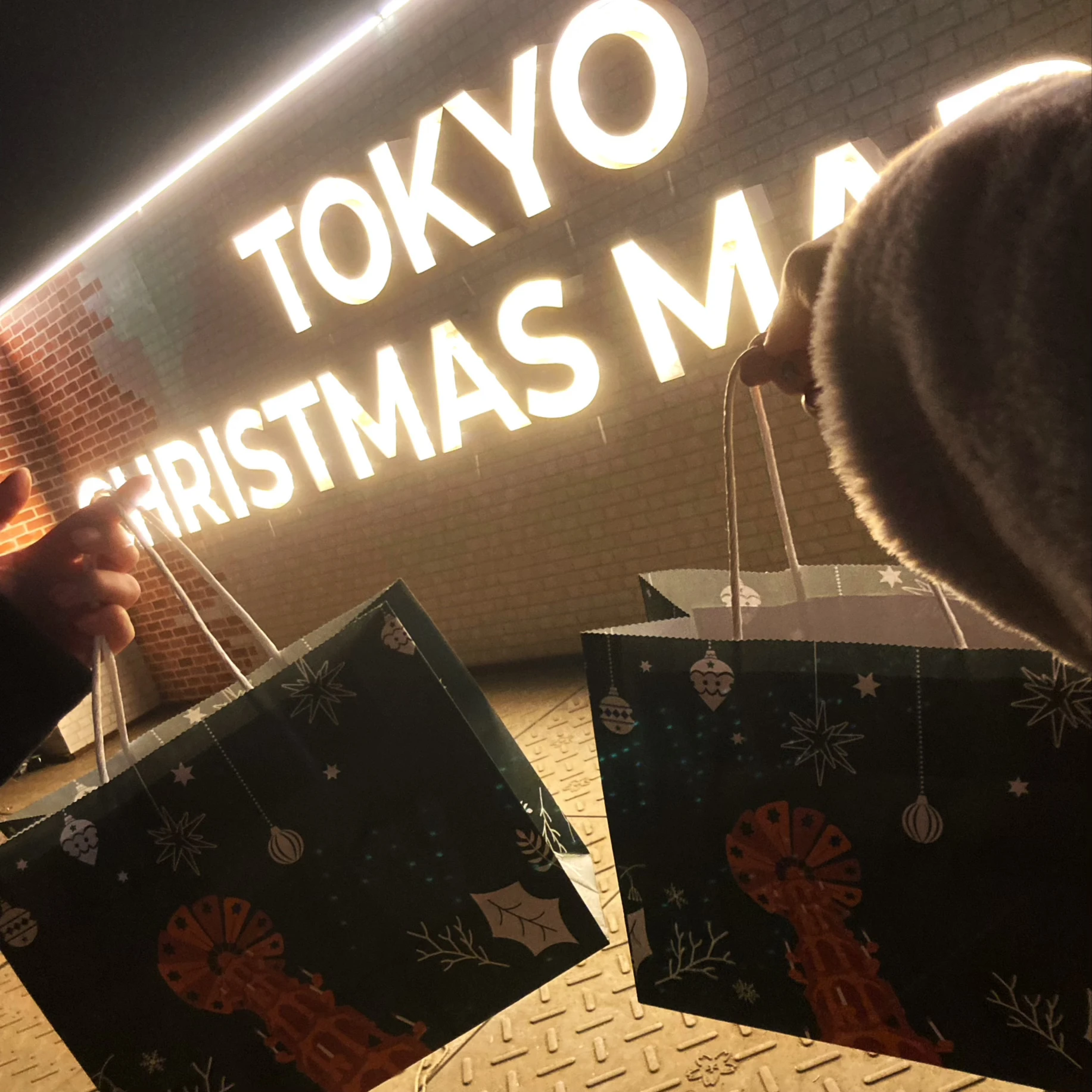 『東京クリスマスマーケット2023 in 明治神宮外苑』入り口のネオンと事前予約特典の紙袋。