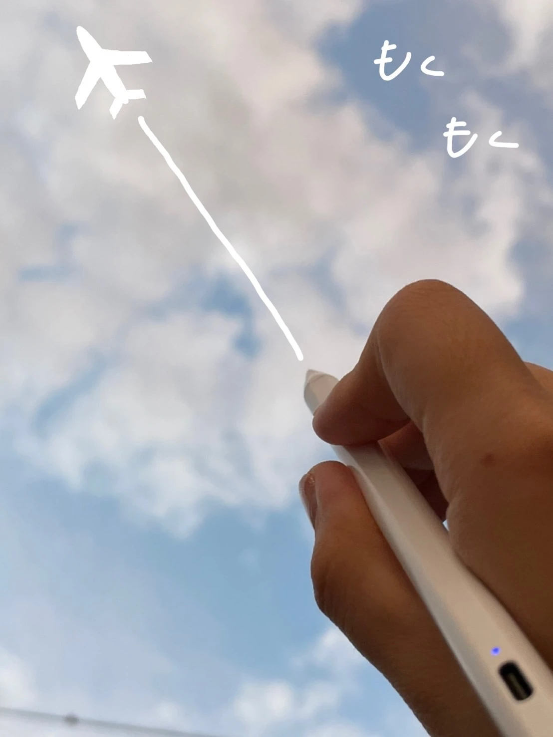 空を写した写真に、飛行機雲のイラストを描いた様子