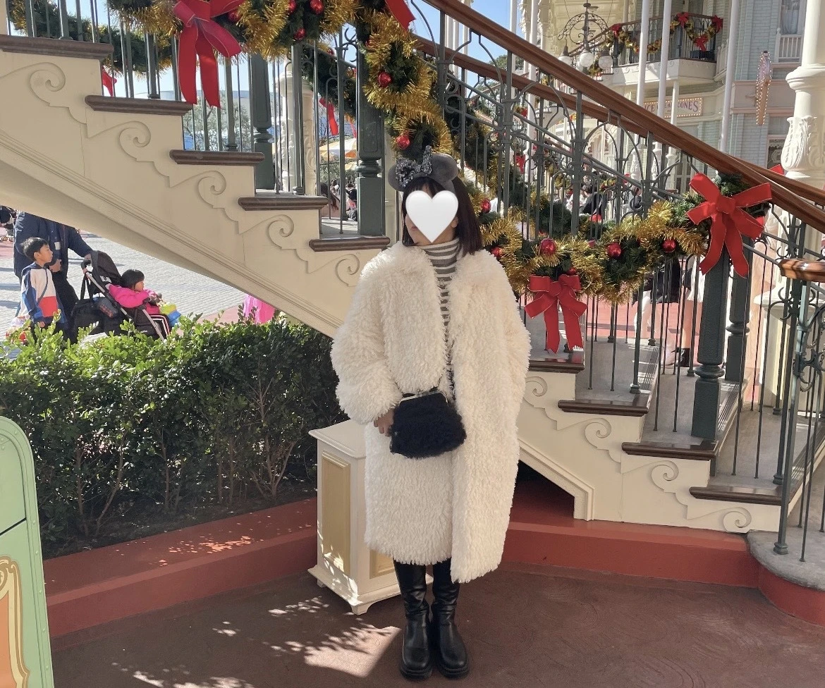 白のファーロングコートを着用しているディズニーランドで撮った写真